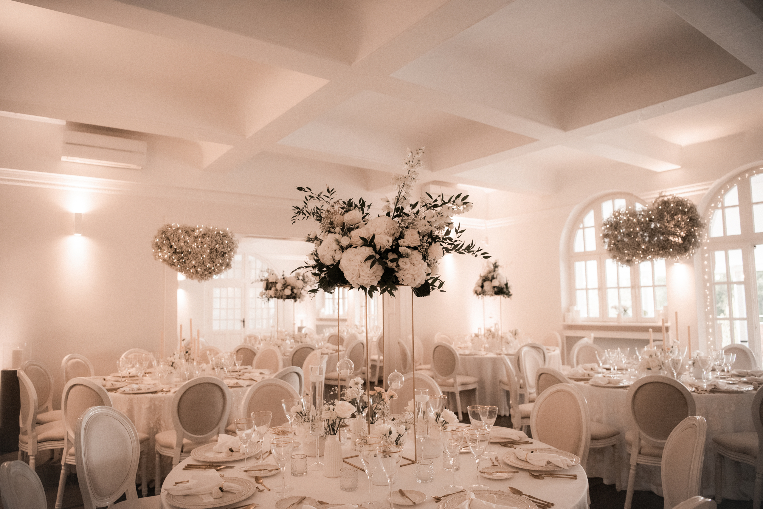 Elegante Hochzeitstischdekoration mit hohen weißen Blumengestecken und schwebender Blumendekoration von Gärtnerei Reinwald Heilbronn.