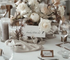 Liebevolle Details für die Hochzeitstafel: weiße Blüten, Trockenblumen und Eukalyptus sorgen für eine natürliche, elegante Stimmung. Blumendekoration mit weißen Blüten, Trockenblumen und Eukalyptus auf einer festlichen Hochzeitstafel.