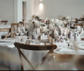 Stilvolle Hochzeitsfloristik für die Festtafel: weiße Blüten, Eukalyptus und Kerzen sorgen für eine elegante, romantische Stimmung. Elegante Hochzeitstafel mit weißen Blumen, Eukalyptus, Kerzen und stilvoller Tischdekoration.
