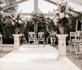 Romantische Traukulisse von Gärtnerei Reinwald: weißer Traubogen, üppige Blumensäulen und elegante Hochzeitsfloristik für eine freie Trauung. Freie Trauung mit weißem Traubogen, Blumensäulen und Hochzeitsfloristik von Gärtnerei Reinwald Heilbronn.