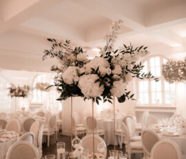 Stilvolle Hochzeitsfloristik von Gärtnerei Reinwald: hohe weiße Blumendekoration mit Hortensien, Rosen und Eukalyptus für eine elegante Hochzeitstafel. Hohe weiße Blumendekoration zur Hochzeit mit Hortensien, Rosen und Eukalyptus von Gärtnerei Reinwald Heilbronn.